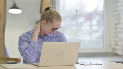 Woman Massaging Neck While Using Laptop Indoors