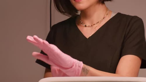 Woman Puts On Pink Gloves in Medical Office