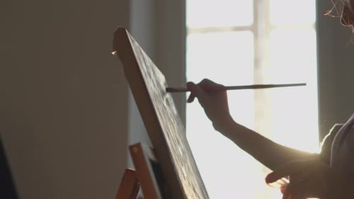 Woman Painting on Canvas with Brush in Studio