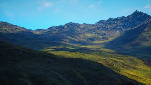 Laderas de color marrón rojizo y picos montañosos cubiertos de nieve