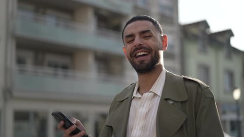 Happy young man laughing and smiling closeup face standing in city street. One Arab of Middle