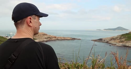 Man in Cap Looking at Sea View from Coastal Cliff