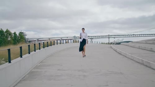 Elegant business woman walking empty road on city street under cloudy sky