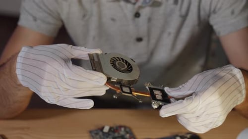 Un reparador de computadoras examina un enfriador portátil polvoriento con un primer plano