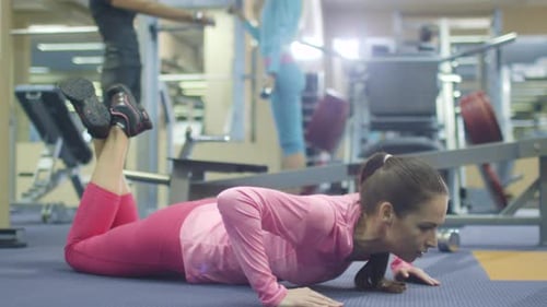 Attractive fit sporty girl is exercising pushups in the gym.