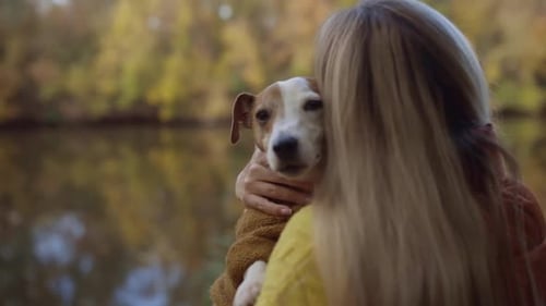 Portrait of a Smiling Young Woman Kissing a Dog in a Field