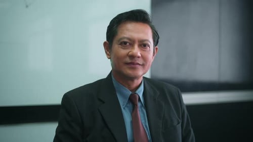 Close up face of asian senior businessman is looking camera in office