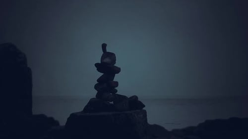 Stacked Stones Create a Serene Monument at the Water Edge During Twilight