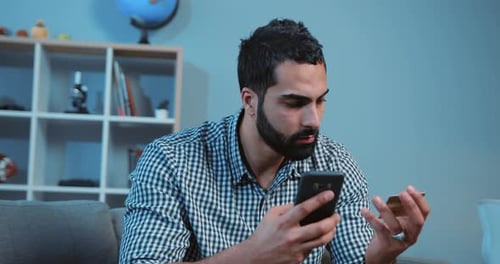 Man Uses Credit Card and Phone on Couch