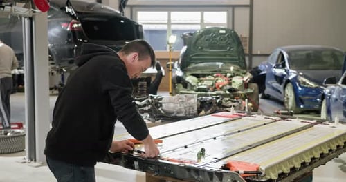 Technician Working On EV Battery In Car Repair Shop