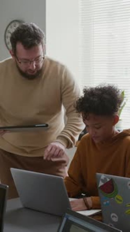 Vertical del profesor dando consejos a un niño dibujando un diagrama en la lección de codificación