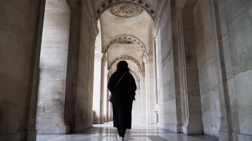 Uma mulher na passarela arqueada do pátio do Museu do Louvre, Paris, França. Foto de rastreamento