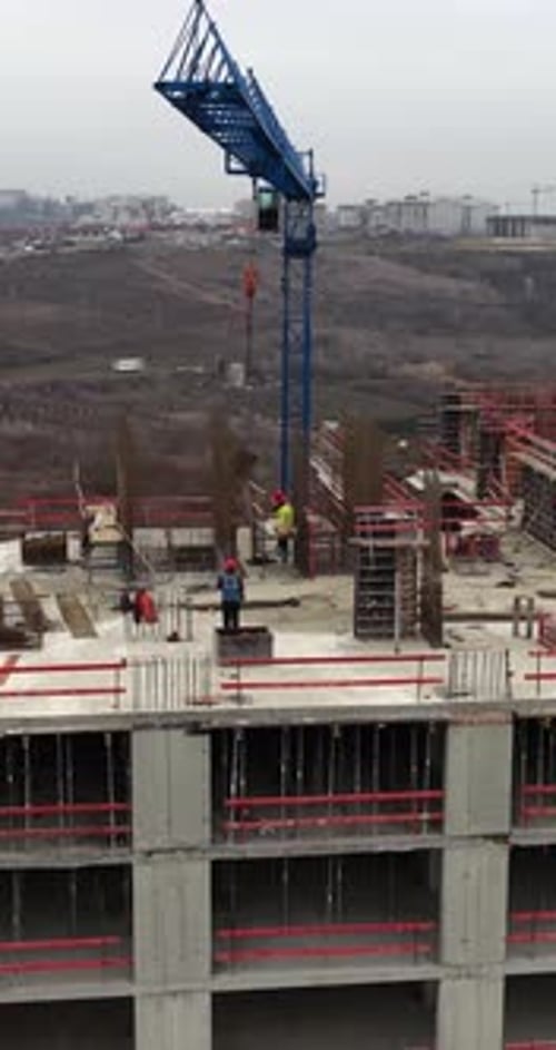 Vertical Aerial Drone Orbit Around Crane Load During Concrete Construction Work