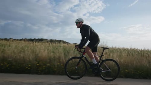 Athletischer männlicher Radfahrer mit Helm beim Fahrradfahren auf malerischen Straßen
