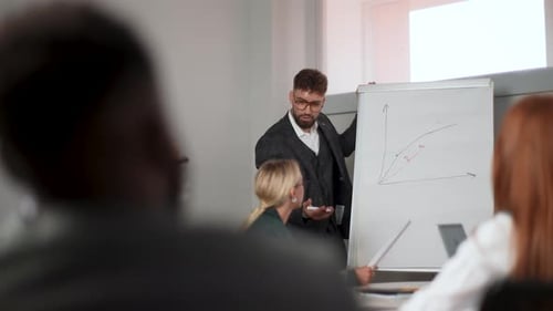 Man Presenting Data on Whiteboard to Colleagues