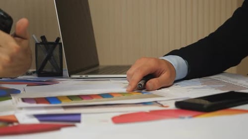 Manos masculinas de dos socios analizando informes financieros en gráficos y tabletas en la oficina