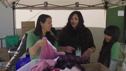Happy Volunteers Sorting Clothing at Clothing Drive in Parking Lot Altruism