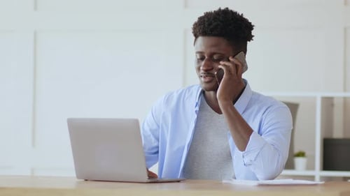 Young Adult Man Using Laptop and Talking on Phone