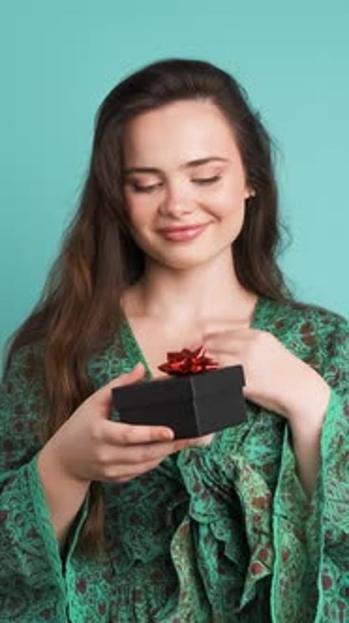 Happy Young Woman Receiving Gift Box in Blue Studio