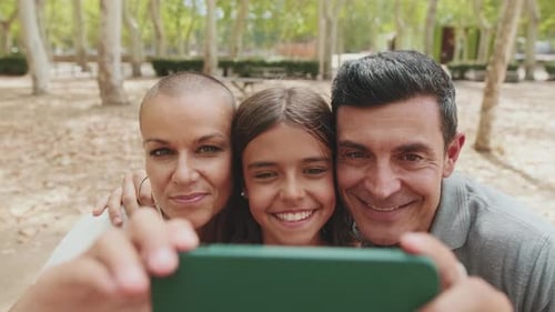 Close up, happy family taking selfie on mobile phone while sitting on park bench