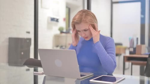 Woman at Desk Works on Laptop with Headache