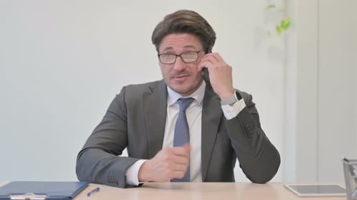 Portrait of Middle Aged Businessman Talking on Phone in Office