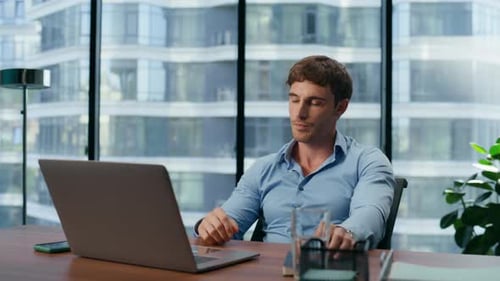 Frustrated Man Working on Laptop in Modern Office