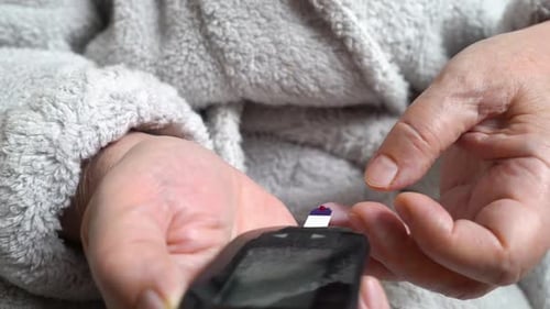 Diabetic Patient Measuring Blood Glucose Level with a Glucometer
