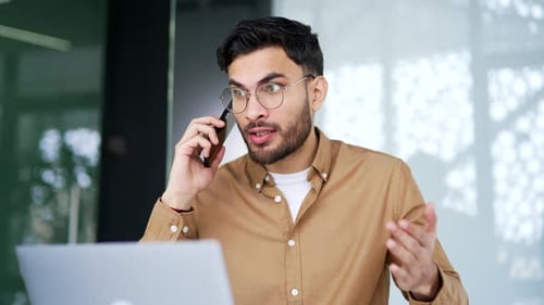 Energetic Man Talking on Phone at Work Desk