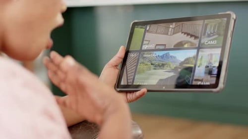 African American woman reviews CCTV security footage on a tablet at home