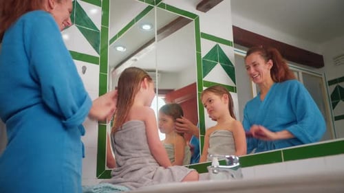 Woman Brushing Girl's Hair in Bathroom