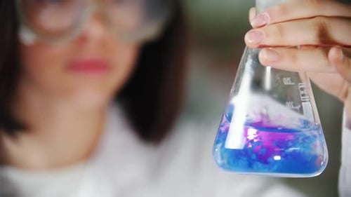 Woman Scientist Holding Beaker with Liquid Mixing