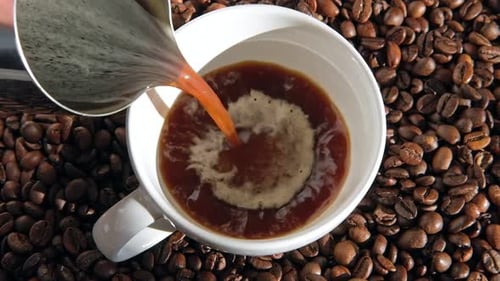 Creamy Coffee Pouring into White Mug