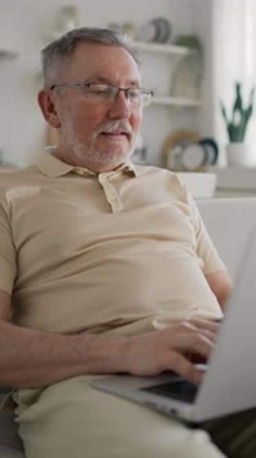 Senior Internet User Working with Laptop at Home Vertical Video Portrait of Happy Retiree Man
