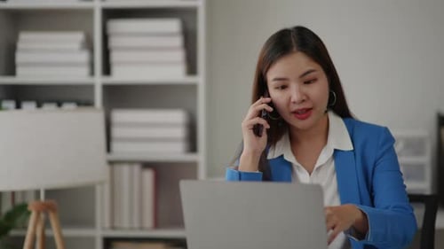 Woman Talking on Phone While Working on Laptop