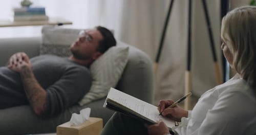 Le thérapeute rédige des notes pendant qu'un patient parle de ses problèmes