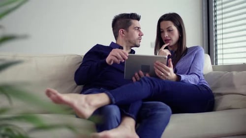 Young couple planning interior decoration for their new home on tablet