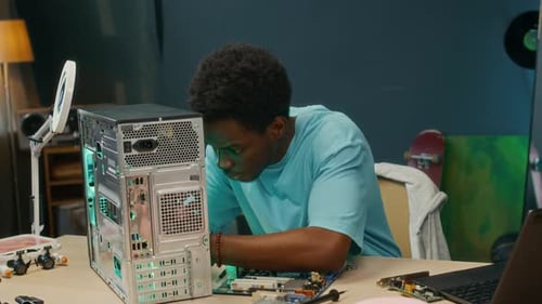 Young Man Examining Computer Case at Home Workshop