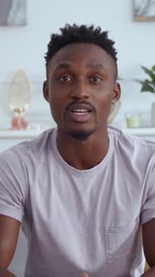 A Young Man Sits Comfortably Indoors in a Casual Shirt That Reflects Contemporary Style