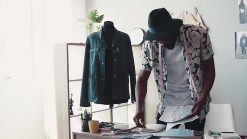 Fashion Designer at Desk with Sketches and Fabrics