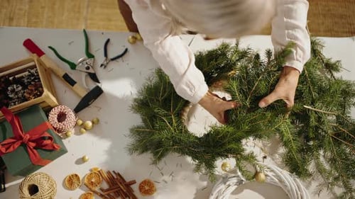 Top View of Senior Woman Making Christmas Wreath From Natural Materials Indoors
