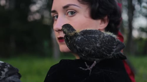 Uma mulher elegante segurando um pássaro em um ambiente natural sereno e tranquilo, cercado por belas