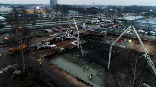 Overhead view of a commercial building site with concrete being poured from mixer trucks