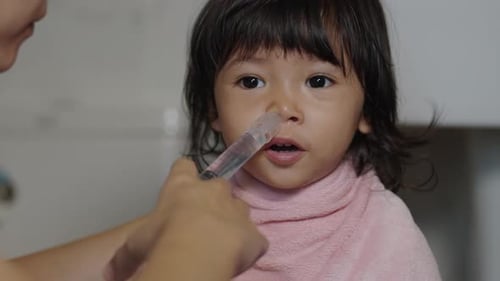 slow-motion of mother making nasal wash for toddler with a syringe and saline. cleaning baby nose