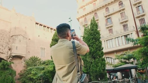 Young man takes photo on the street of the old city. Back view