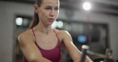 A Young Beautiful Brunette Girl in Sportswear is Exercising on a Machine in the Gym Doing Exercises
