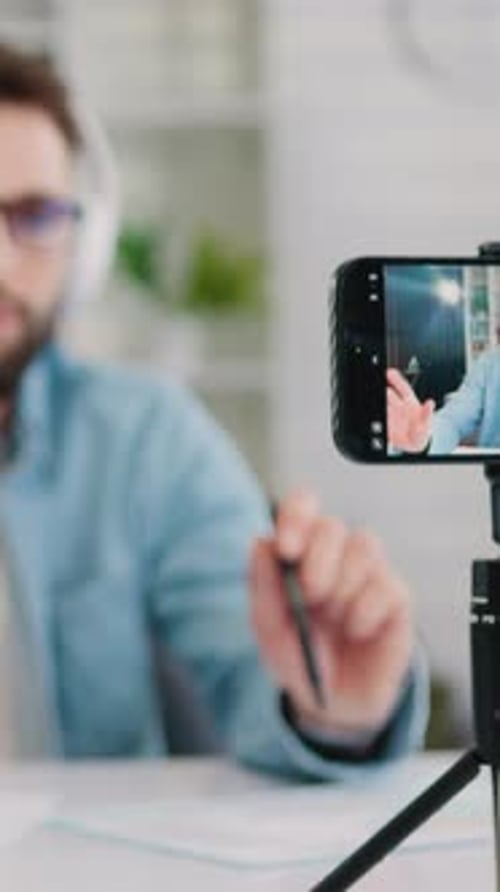 Man Records Video with Phone on Tripod Indoors