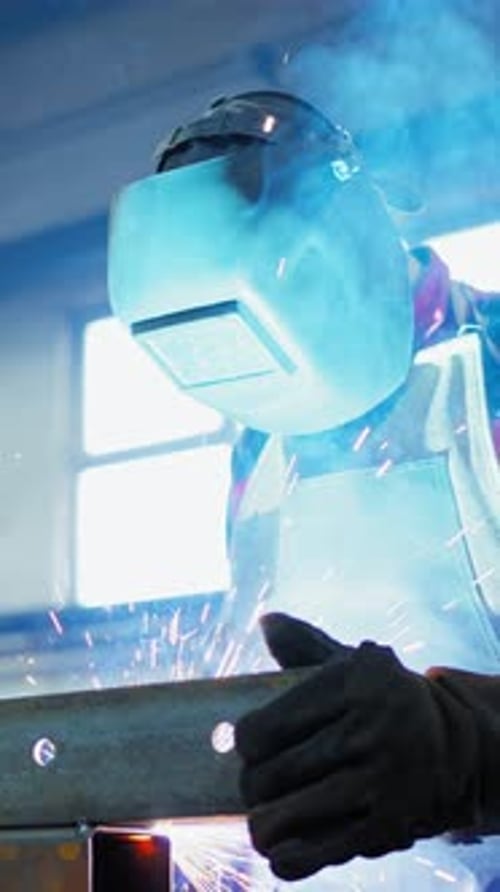 Soudeur créant des étincelles dans un atelier avec une lumière bleue brillante