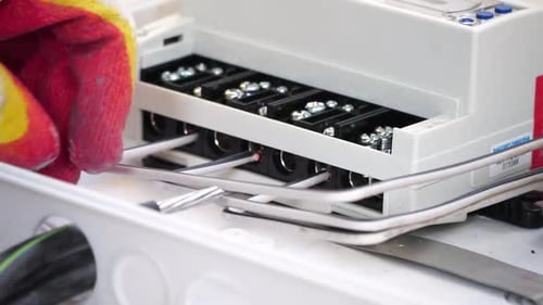 Hands connecting white wires to gray electrical box