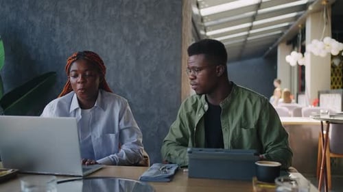 A Male and Female African American Duo are Having Business Negotiations in a Cafe Animatedly
